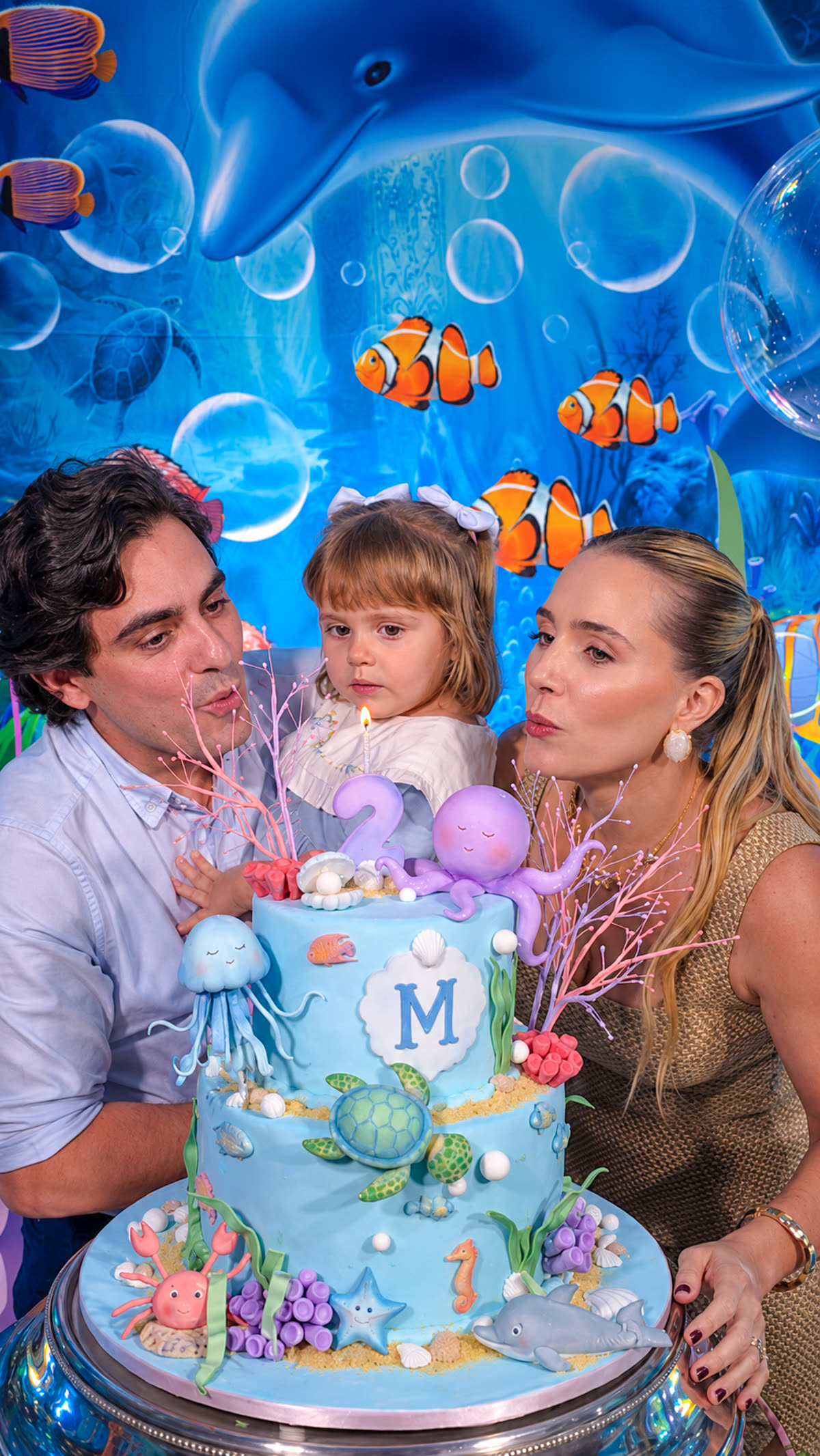 Maria com os pais soprando a velinha de aniversário