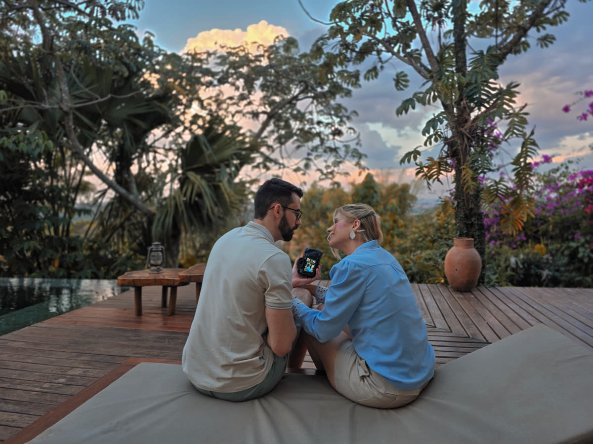 Casal revendo fotos na câmera ao pôr do sol